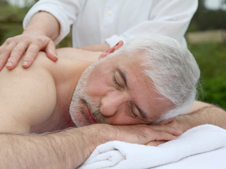 older man gets back massage outdoors