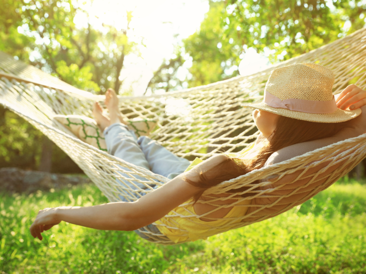 woman with hat relaxes in hammock