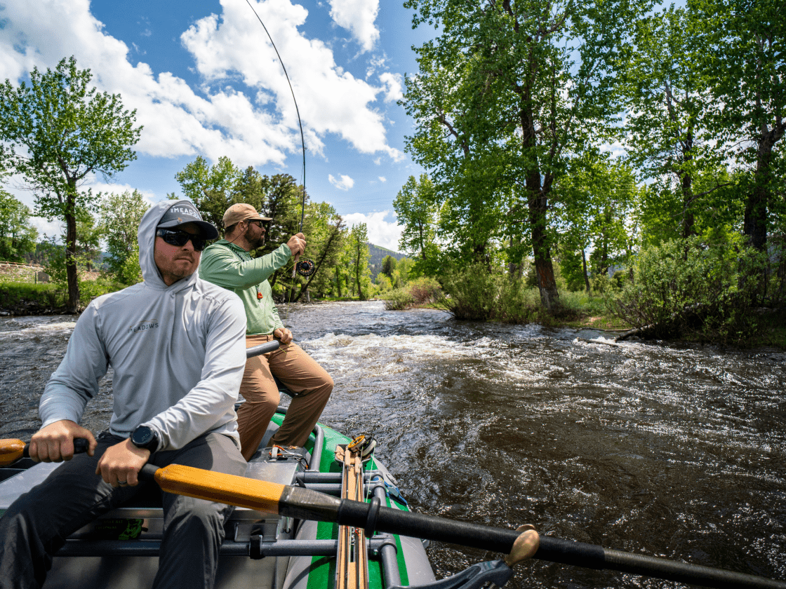 two anglers float down a river and fly fish for trout