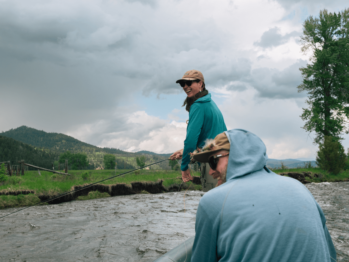two anglers float in a raft and fly fish for trout