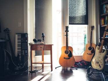 three guitars sit on stands in a room with white walls