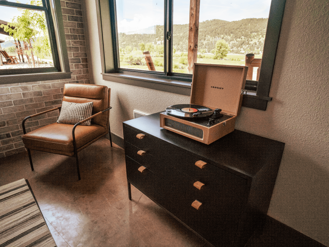 a single chair and a record player with large windows where you can see the landscape in the background