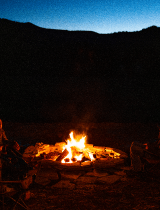 a campfire with a dark background and people sitting around it
