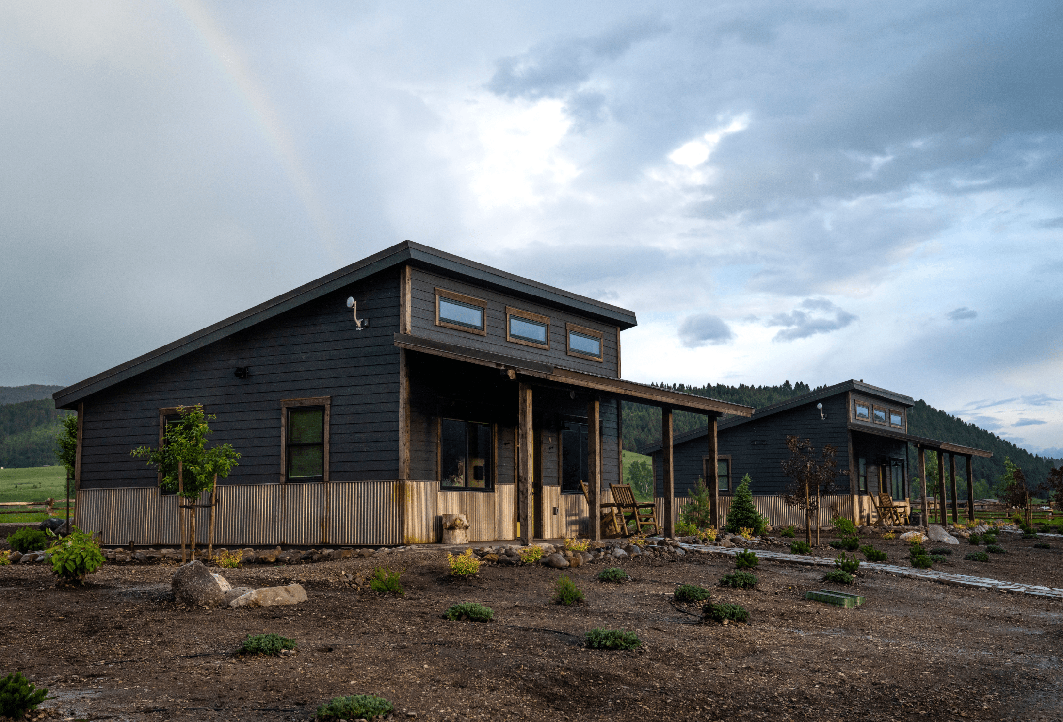 two cabins in morning light with a rainbow in the background