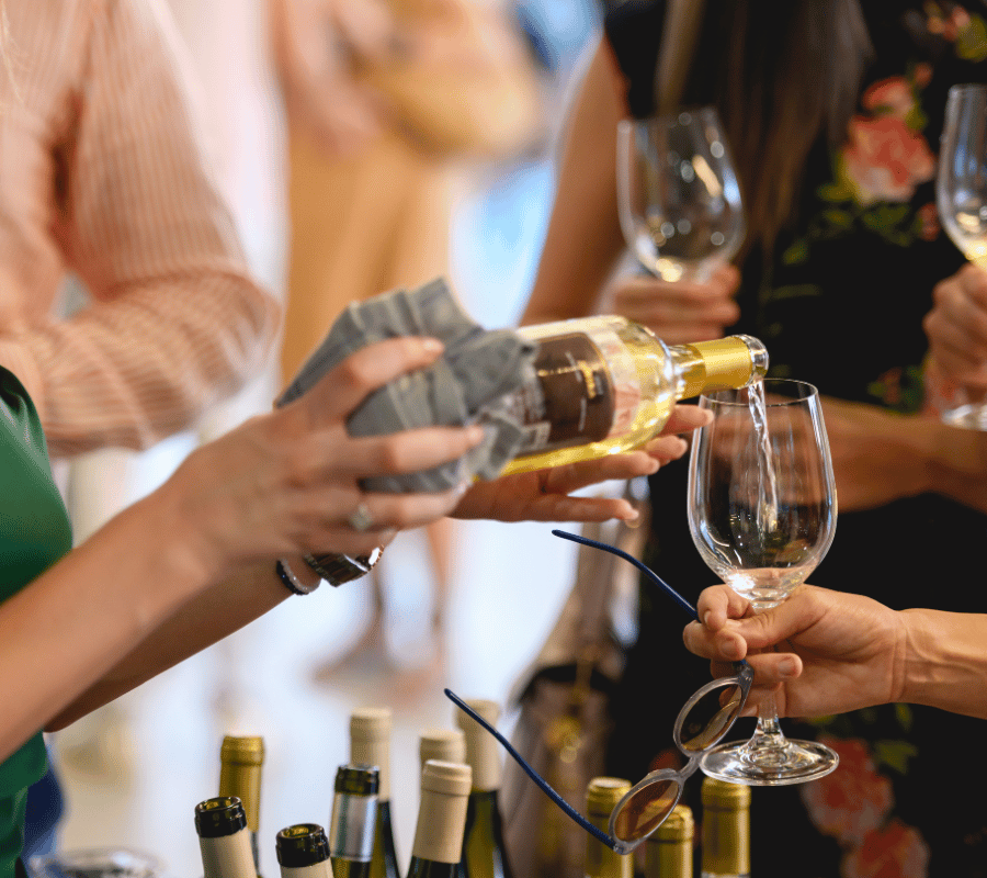 multiple people holding wine glasses and tasting