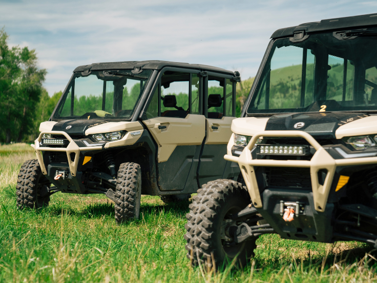 two Can Am UTV's parked on grass next to each other