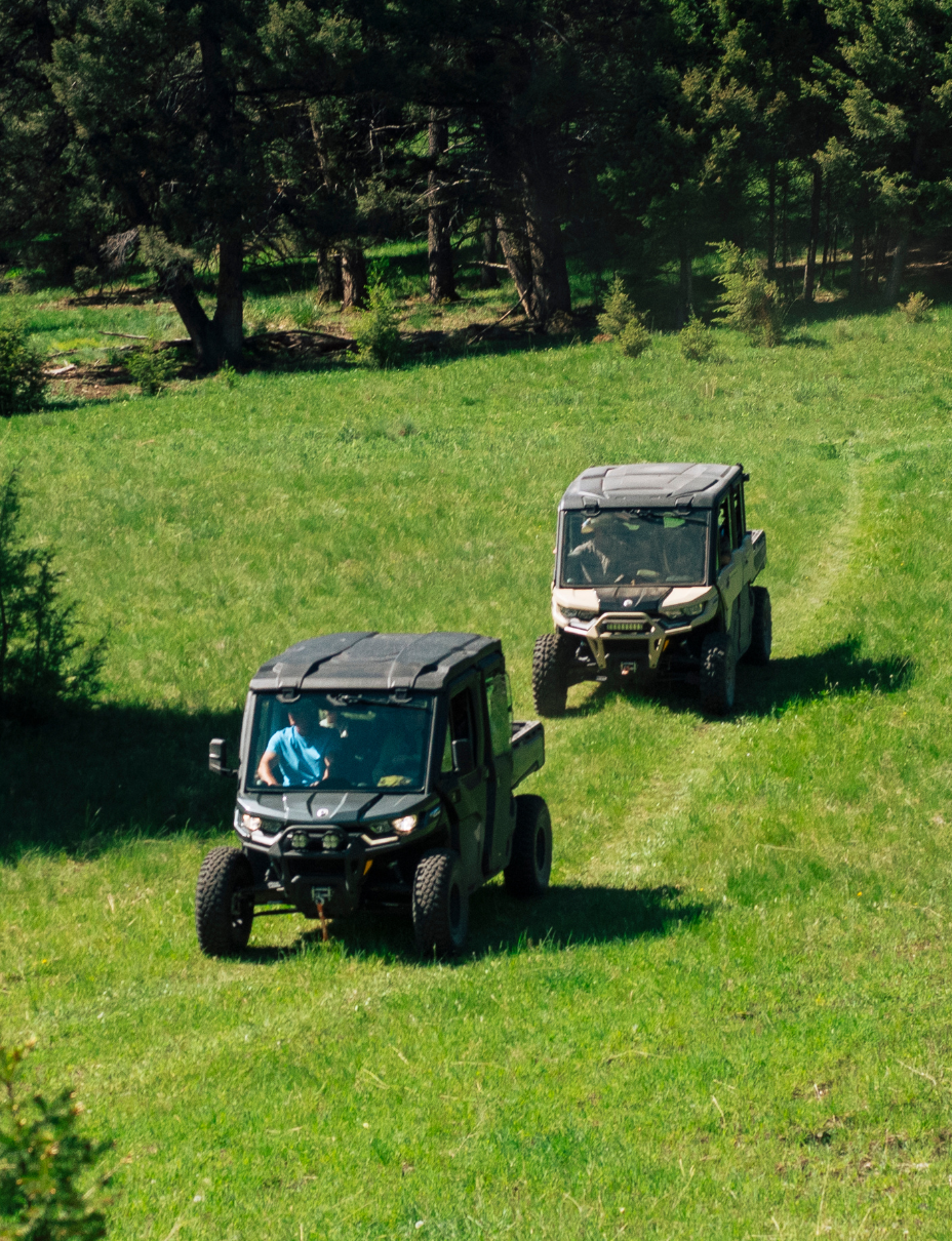 two can am UTVS drive down a grassy hill