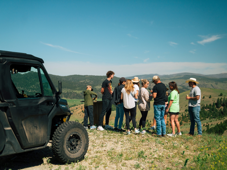 A family stands at a scenic view point with a Can Am UTV on the side