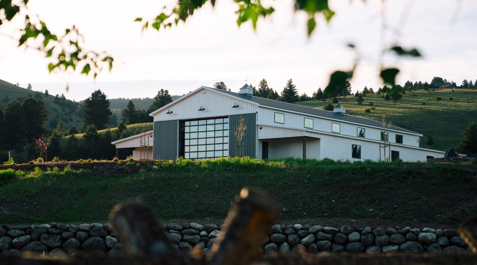 a white barn on a green grassy hill