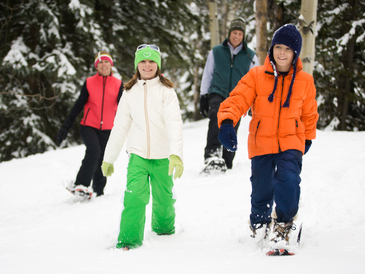 a family of snowshoers explore snow covered trails