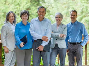 a group of business professionals stand together in front of a forested background