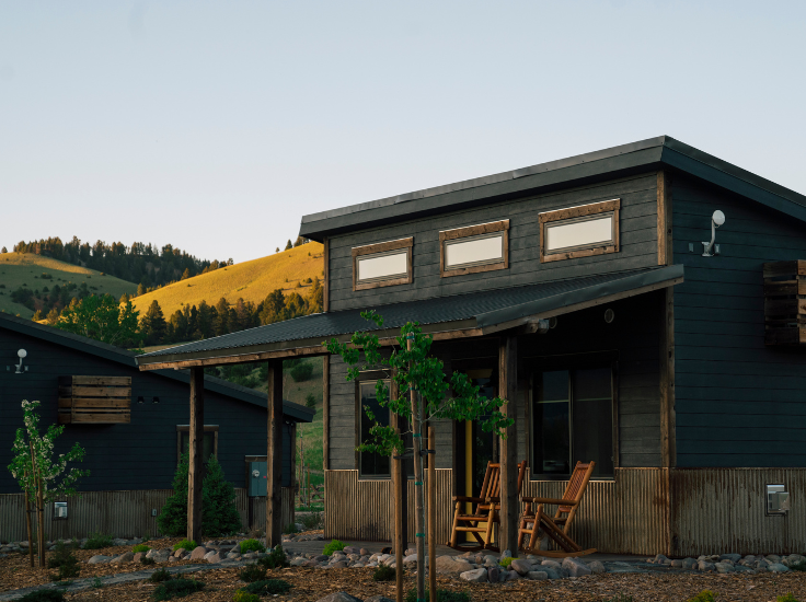 a mountain-rustic cabin at sunset with green grassy hills in the background