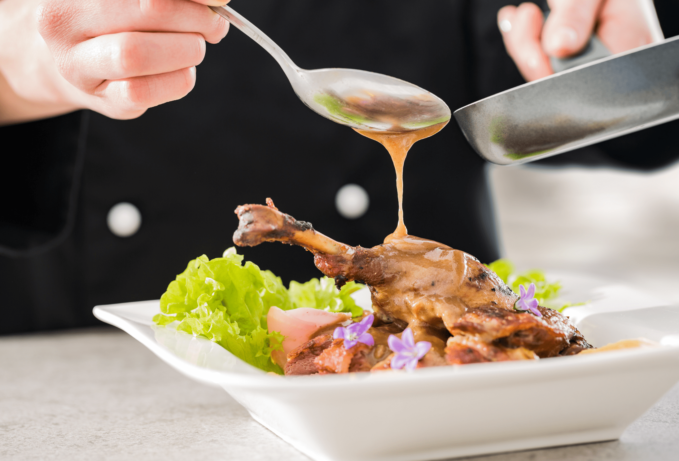 a chef pour sauce over a plate of food