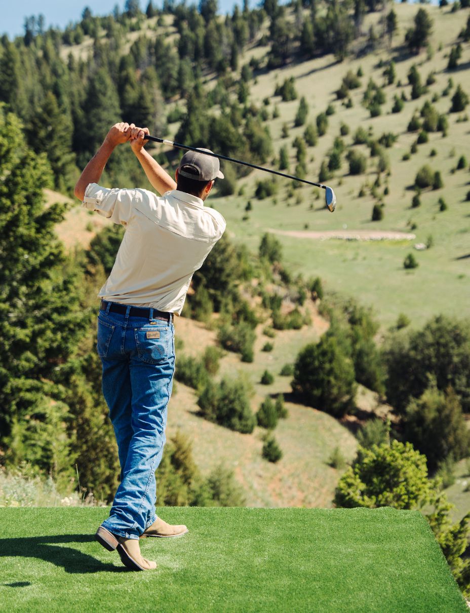man swings a golf club at a mountain golf course in Montana