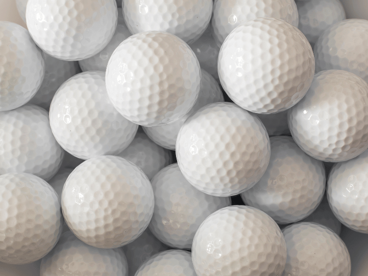 many white golf balls in a pile