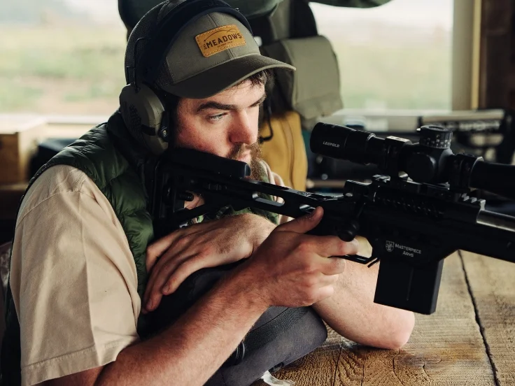 a man holds a rifle and takes aim at a course