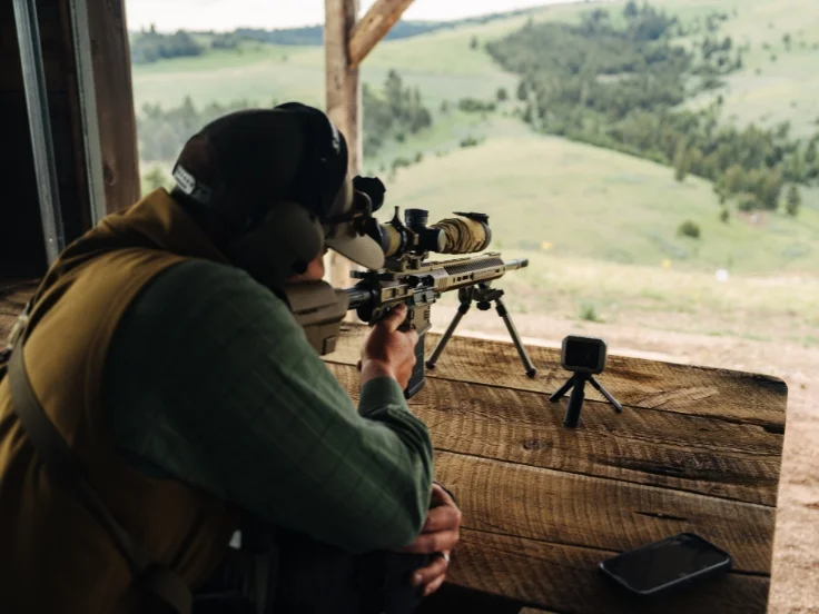 a man shoots a rifle at long range on a course