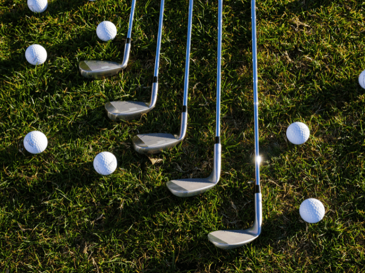 multiple golf clubs and balls on grass