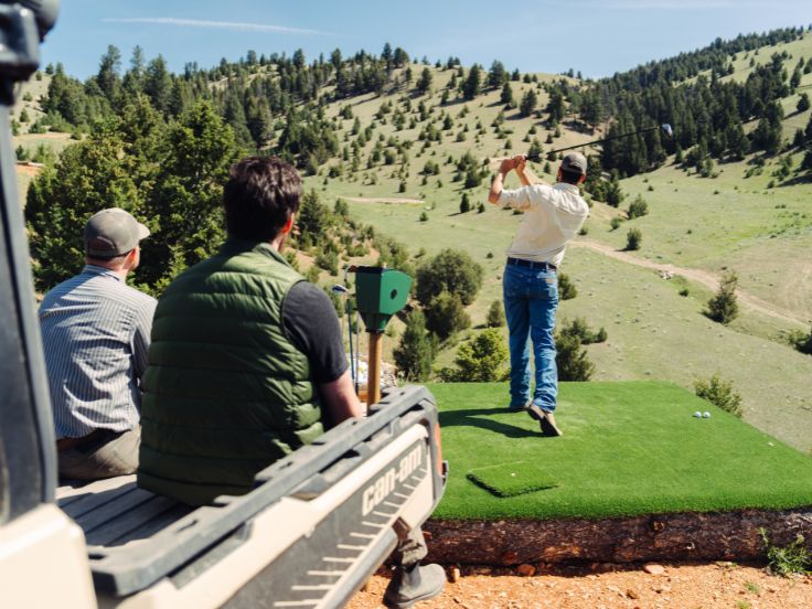 man hits a golf ball in the mountains of montana