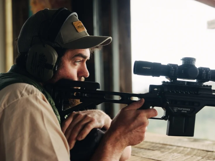 a man holds a rifle while doing long range shooting