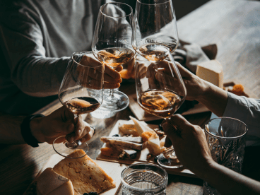 a group of people put wine glasses together over food