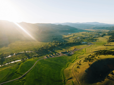 aerial view of a large green valley and a resort ranch property with several cabins