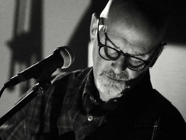 a man with glasses on singing a song into a microphone