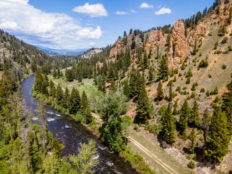 a large canyon with a river in the middle and a green boat floating down it