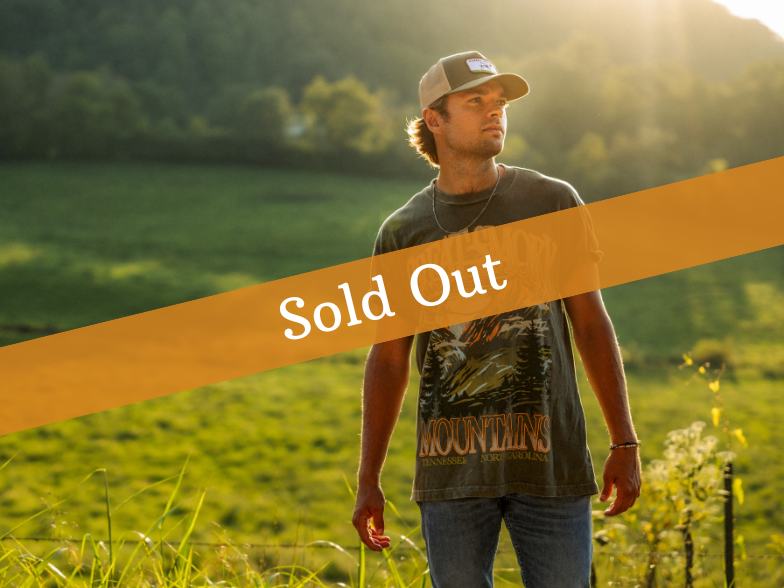 man standing in field with a banner overlaid on the image that says "sold out"