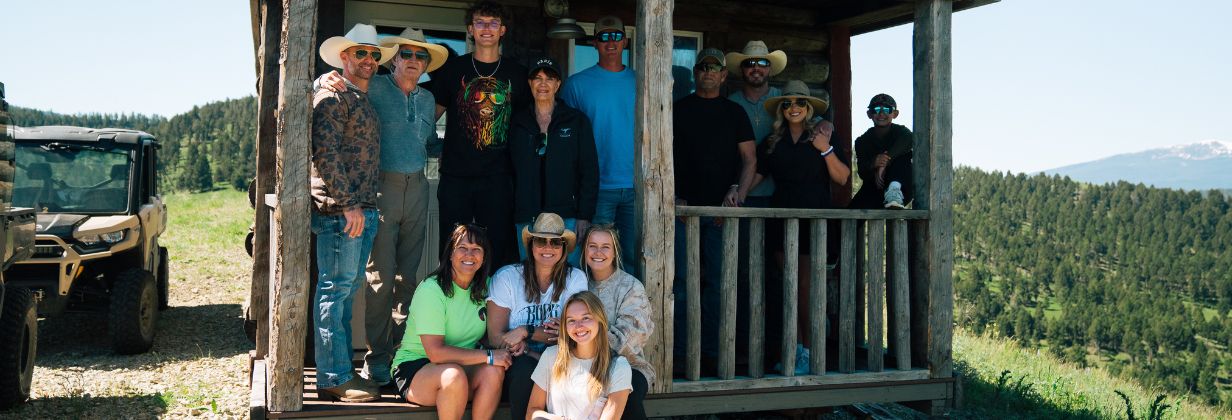a group of people standing in front of a cabin on a hillside
