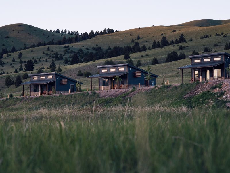 a grassy hill with three cabins on it