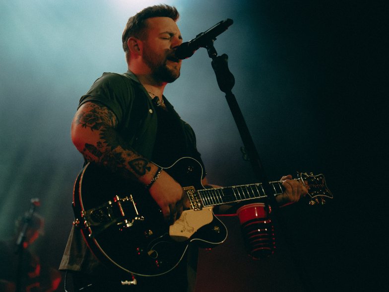 man stands in front of a microphone and sings while playing guitar