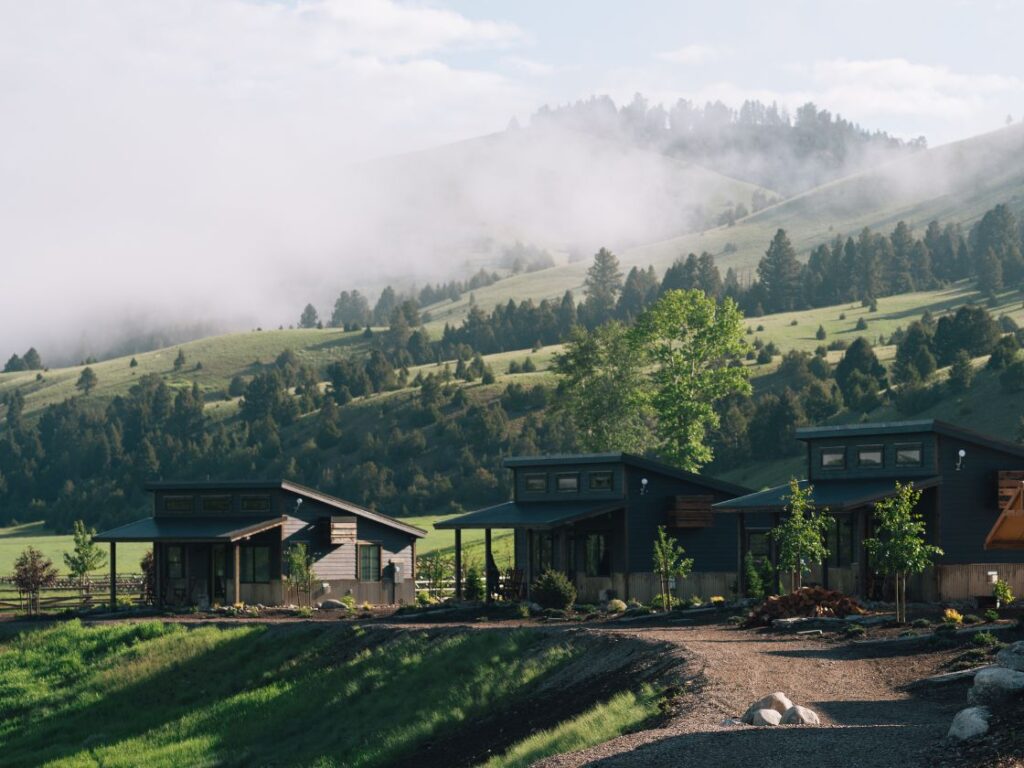 3 cabins in front of a green grassy hillside