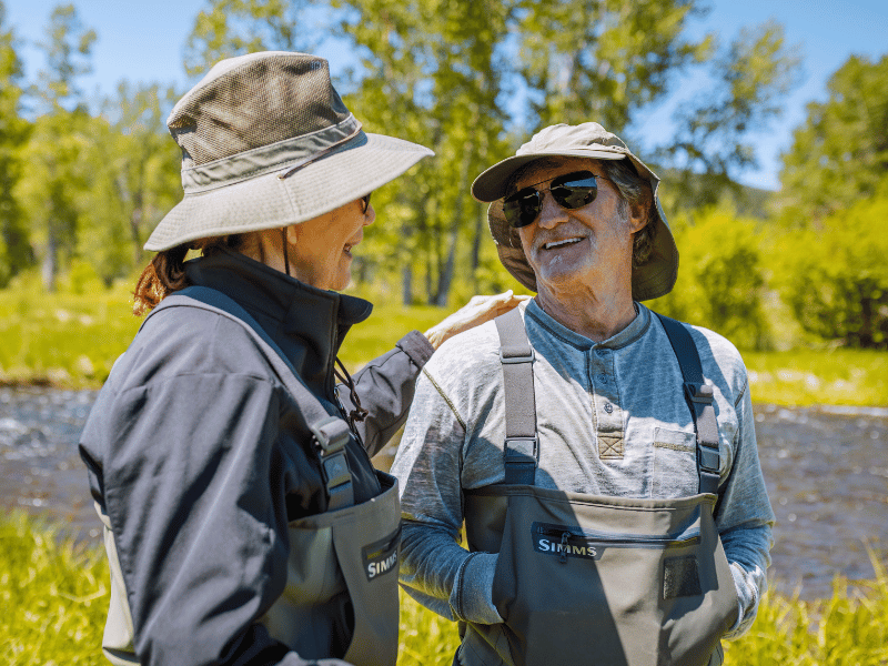 two people standing near a river and laughing together