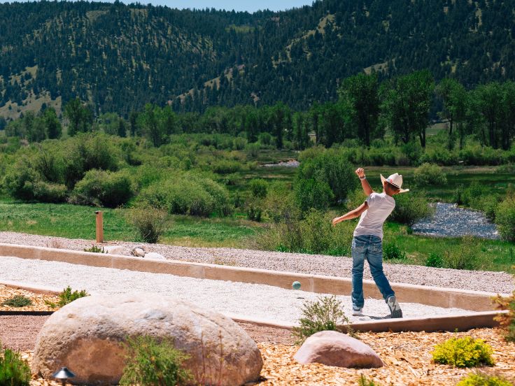 a boy places bocce in front of a river valley