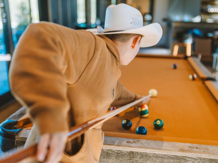 boy playing pool on an orange billiards table