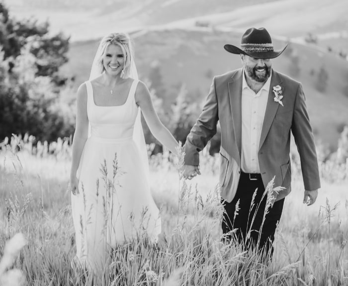 a bride and groom walking in a field