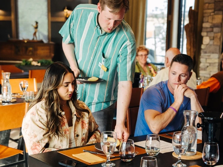a server brings food to a couple at a table