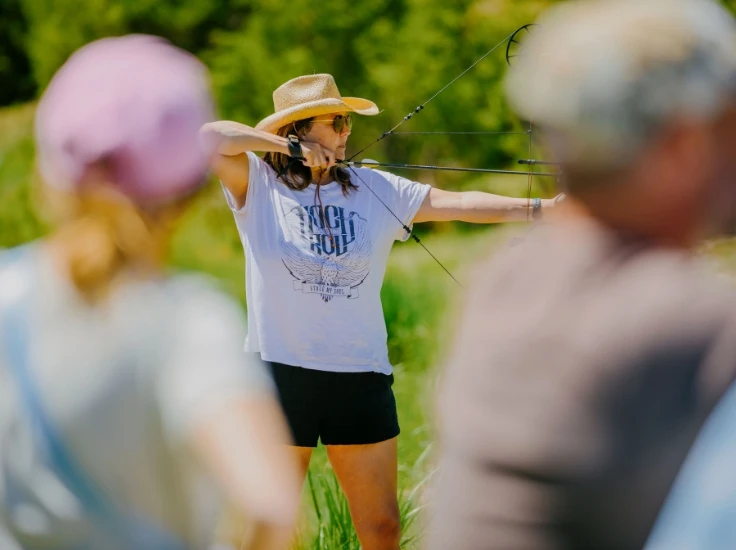 a woman pulls back on a bow while doing archery