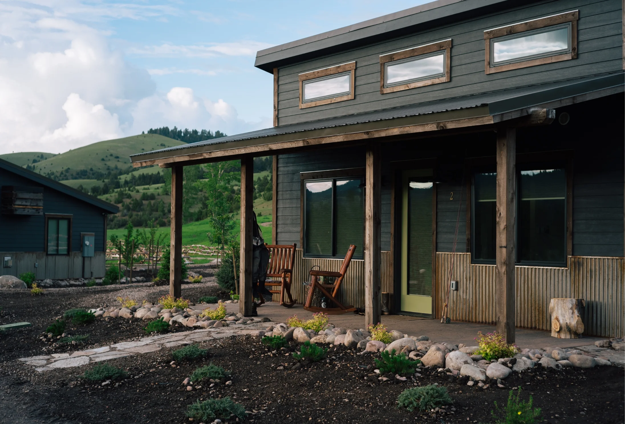 a luxury cabin with a large front porch in front of a green mountain