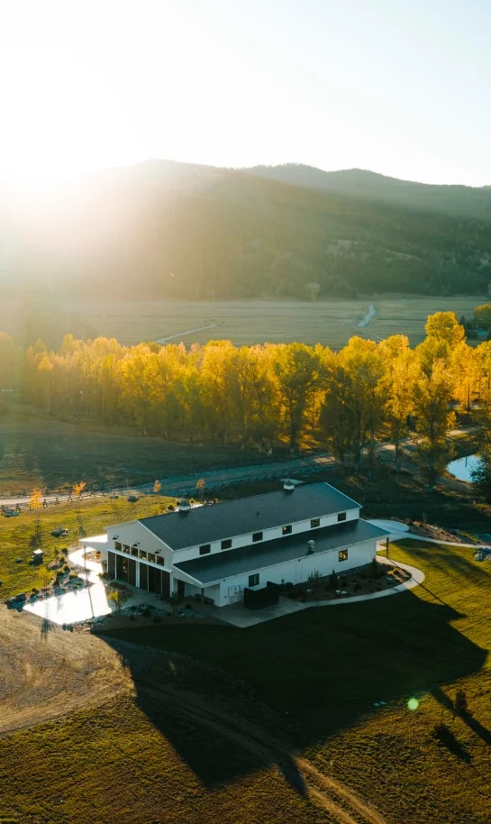 a large white barn in the middle of a river valley in Montana