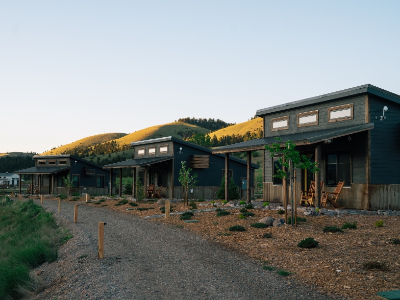 a group of cabins in front of a green grassy mountain in Montana