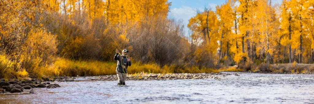 an angler casts a fly fishing rod on Montana's rock creek in the fall