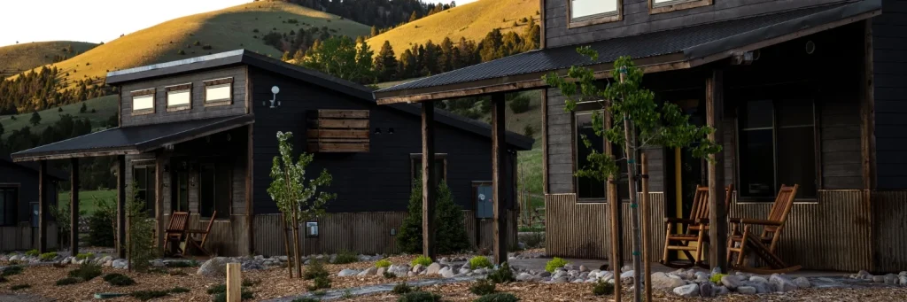 Two cabins set in front of a grassy hillside at sunset